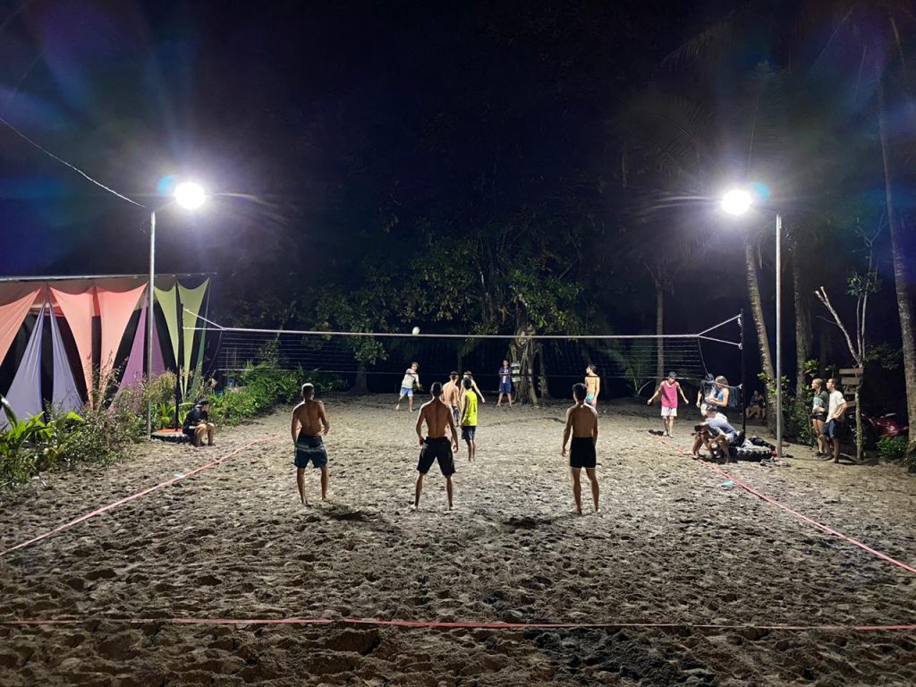 men and boys play volleyball at night